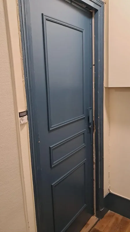 Porte palière bleue avec verrou et bâti abîmé